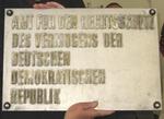 Hände halten Tafel einer ehemaligen DDR-Behörde